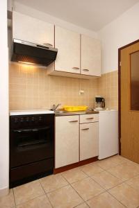 eine Küche mit einem schwarzen Backofen und weißen Geräten in der Unterkunft Apartment Kneza 4342a in Račišće