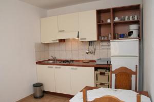 a kitchen with white cabinets and a white refrigerator at Apartment Zarace - Gdinj 4598a in Gdinj