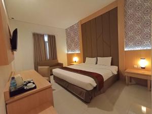 a hotel room with a large bed and a chair at Al Azhar Azhima Hotel Resort and Convention in Solo