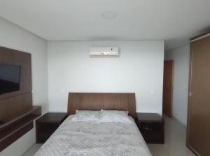 Schlafzimmer mit einem Bett und einem Flachbild-TV in der Unterkunft Praia do Morro Frente para o Mar in Guarapari