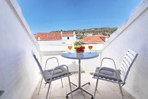 einen Tisch auf einem Balkon mit 2 Stühlen und Getränken in der Unterkunft Apartments by the sea Vela Luka, Korcula - 4449 in Vela Luka