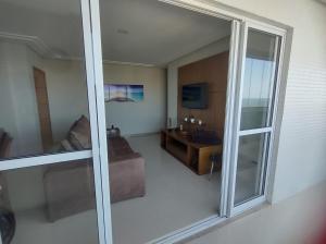 een woonkamer met een glazen schuifdeur bij Praia do Morro Frente para o Mar in Guarapari