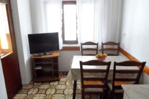 una sala da pranzo con tavolo, sedie e TV di Apartments by the sea Lumbarda, Korcula - 4369 a Lumbarda (Lombarda)