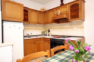 a kitchen with wooden cabinets and a table with purple flowers at Apartments and rooms by the sea Racisce, Korcula - 4341 in Račišće