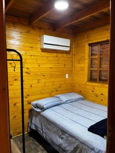 um quarto com uma cama numa parede de madeira em Cabana do Embaú Experience em Palhoça