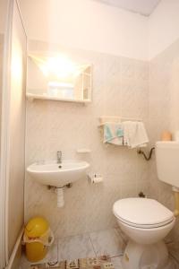 a white bathroom with a toilet and a sink at Double Room Lumbarda 4436d in Lumbarda
