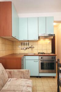 eine Küche mit blauen Schränken, einem Herd und einer Couch in der Unterkunft Apartments by the sea Lumbarda, Korcula - 4440 in Lumbarda