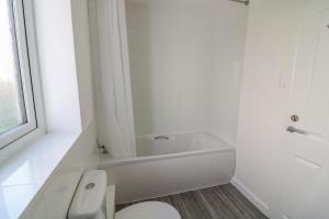 a white bathroom with a toilet and a bath tub at Waters Reach in Kingsbridge