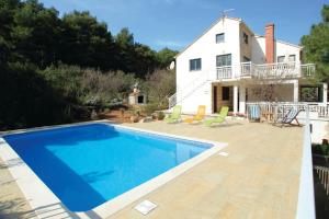 a villa with a swimming pool in front of a house at Seaside apartments with a swimming pool Lumbarda, Korcula - 4404 in Lumbarda