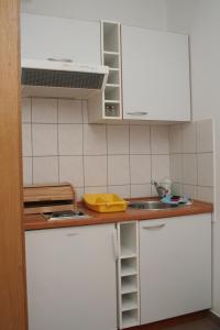 uma cozinha com armários brancos e um lavatório em Apartment Orebic 4494d em Orebić