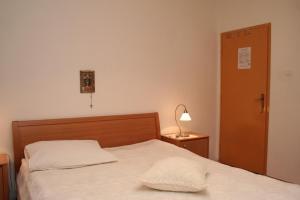 Rooms by the sea Vrboska (Hvar) - 4600 في فربوسكا: غرفة نوم بسرير ومصباح وباب