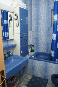 Rooms by the sea Vrboska (Hvar) - 4600 في فربوسكا: حمام أزرق مع حوض ومغسلة
