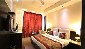 Habitación de hotel con cama y cortina roja en The Prime Balaji Deluxe @ New Delhi Railway Station en Nueva Delhi