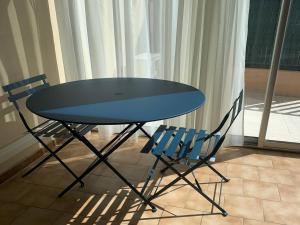 une table et deux chaises assises à côté d'une fenêtre dans l'établissement Appartement Cavalaire-sur-Mer, 1 pièce, 4 personnes - FR-1-226B-116, à Cavalaire-sur-Mer
