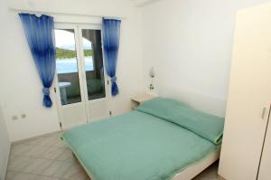 a bedroom with a bed with blue curtains and a window at Apartments by the sea Luka Dubrava, Peljesac - 4568 in Janjina