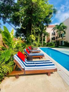 a row of lounge chairs next to a swimming pool at Villa Tendenza Condo in Playa del Carmen