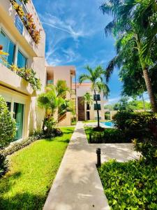 a walkway leading to a building with palm trees at 5th AVENUE oasis 8 personas in Playa del Carmen