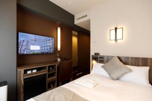 a bedroom with a bed and a flat screen tv at President Hotel Hakata in Fukuoka