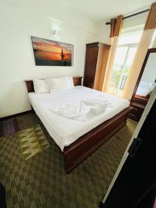 a bedroom with a large bed with white sheets at The Grand Royal Luxury Apartment in Nuwara Eliya