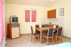 a kitchen with a table and chairs and a television at Family friendly seaside apartments Cove Jagodna - Brusje, Hvar - 4606 in Brusje