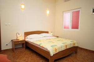 a bedroom with a bed with a nightstand and a window at Family friendly seaside apartments Cove Jagodna - Brusje, Hvar - 4606 in Brusje