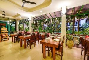 a restaurant with wooden tables and chairs and windows at Coco Retreat Phuket Resort and Spa - SHA Plus in Chalong 