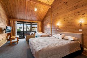 een slaapkamer met 2 bedden in een houten kamer bij Aspiring Lodge Motel in Wanaka