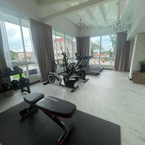 een fitnessruimte met diverse fitnessapparatuur in een kamer met ramen bij Christella Hotel Laemchabang in Si Racha