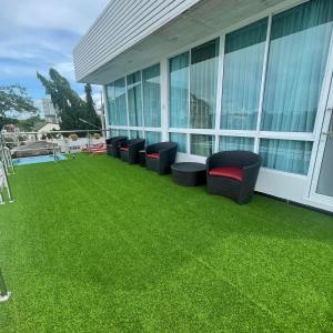 a patio with green grass and chairs on a building at Christella Hotel Laemchabang in Si Racha