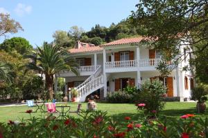 uma grande casa branca com um quintal com flores em Villa Karidia em Asprogerakata