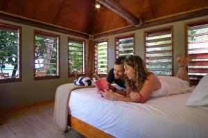 Un uomo e una donna stesi su un letto con un libro di Barefoot Manta Island Resort a Drawaqa Island