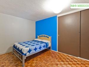 Un pequeño dormitorio con una pared azul y una cama en B&B México Roma Norte, en Ciudad de México