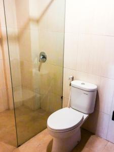 a bathroom with a toilet and a glass shower at RedDoorz At Hotel Gajah Mada Palu in Palu