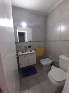 a white bathroom with a toilet and a sink at Arecas in Villa Carlos Paz