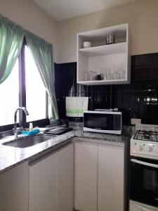 a kitchen with a sink and a microwave at Arecas in Villa Carlos Paz