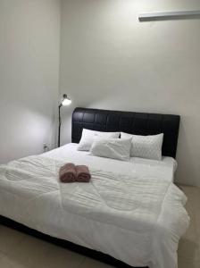 ein großes weißes Bett mit zwei braunen Handtüchern darauf in der Unterkunft OrchidVilla Homestay at Southville Apartment in Kampong Parit