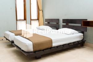 2 Betten auf einem hölzernen Bettrahmen in einem Zimmer in der Unterkunft Homestay Rumah Citra Indah Syariah Mitra RedDoorz in Bukittinggi