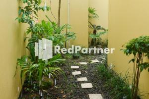 un panneau rouge partenaire dans une pièce avec des plantes dans l'établissement Homestay Rumah Citra Indah Syariah Mitra RedDoorz, à Bukittinggi