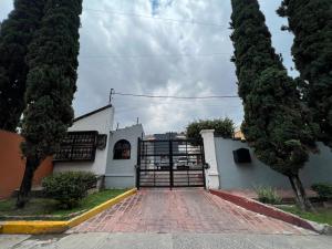 a white building with a gate and some trees at Comfortable apartment with parking, best location in Guadalajara