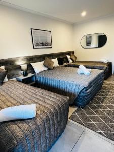a hotel room with two beds and a mirror at Y Motels Gympie in Gympie