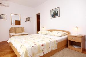 een slaapkamer met een bed en een stoel bij Apartments by the sea Orebic, Peljesac - 4525 in Orebić