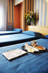 a hotel room with two beds and a tray of food at Hotel Garda in Milan