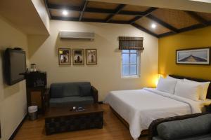 a bedroom with a bed and a chair and a tv at The Richmond in Pondicherry