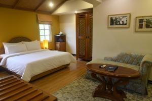 a bedroom with a bed and a table and a couch at The Richmond in Puducherry