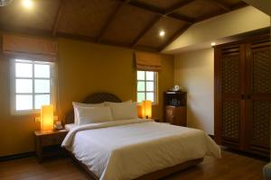 um quarto com uma grande cama branca e 2 janelas em The Richmond em Pondicherry