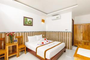 a hotel room with a bed and a table and a desk at Ngoc Qui Bungalow in Phu Quoc