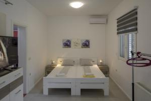 um quarto branco com uma cama e uma televisão em Apartments with a parking space Zuljana, Peljesac - 4573 em Zuljana