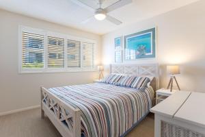 a bedroom with a bed and two windows at Coral Sea Apartments in Maroochydore