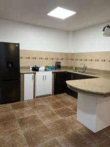 a kitchen with a black refrigerator and a counter at The Royalty Inn ApartmentHotel #1 in Guayaquil