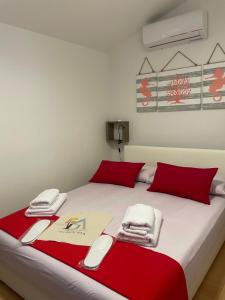 a bed with red pillows and towels on it at Residence4a-Appartamento Rosso in Ravni